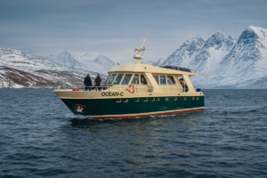 Jacht Ocean C płynący podczas rejsu po Svalbardzie w otoczeniu gór zimowych fiordów.