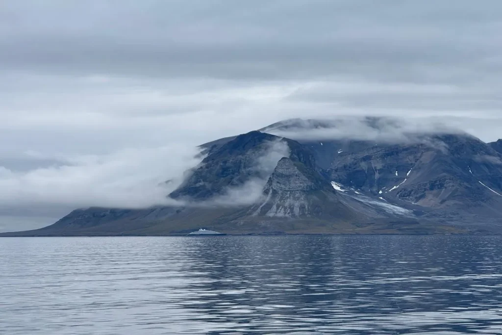 Góry Svalbardu spowite arktyczną mgłą nad spokojnym morzem
