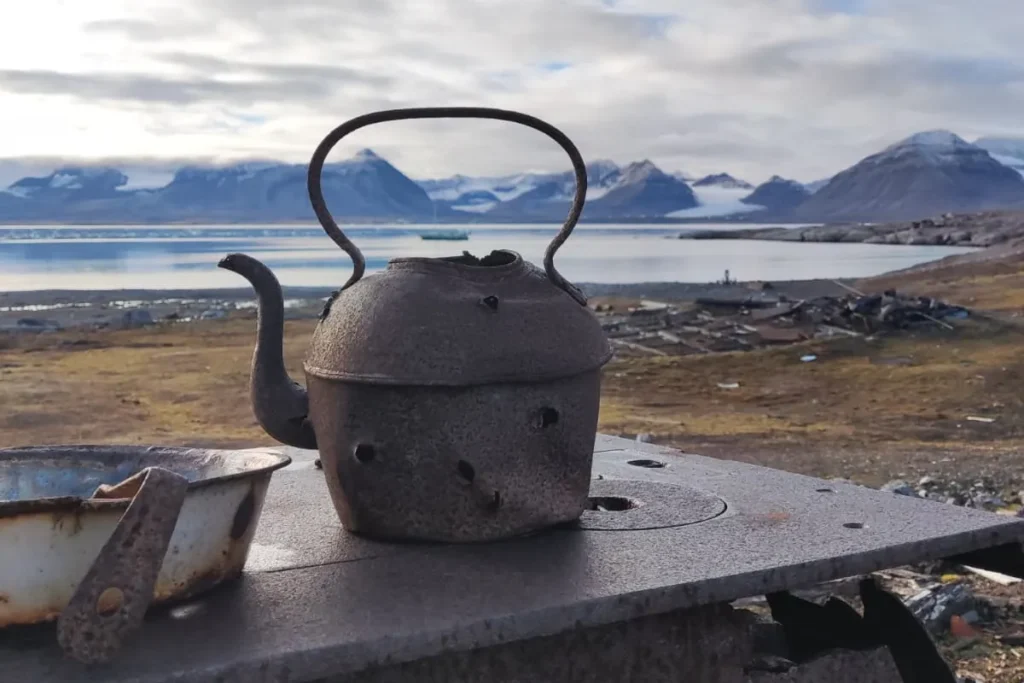 zardzewiały czajnik na tle fiordu i gór lodowych w Kongsfjorden, Svalbard