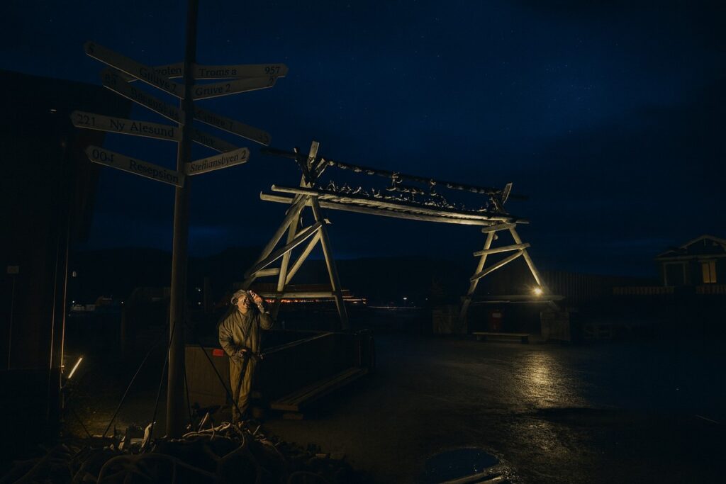 noc w Longyearbyen, oświetlony znak kierunkowy i tradycyjna konstrukcja z poroży