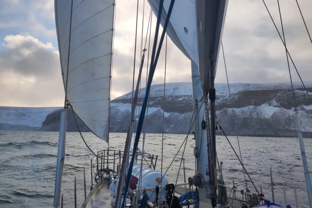Załoga obserwuje klify Alkefjellet z pokładu jachtu, Svalbard