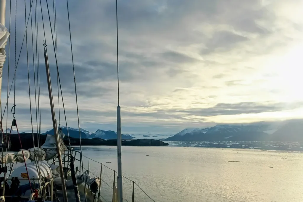 Pokład jachtu płynącego po wodach Kongsfjorden na Svalbardzie, w otoczeniu gór i lodu