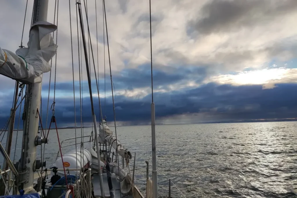 Pokład jachtu żaglowego Ocean B z widokiem na pochmurne, arktyczne niebo i spokojne morze