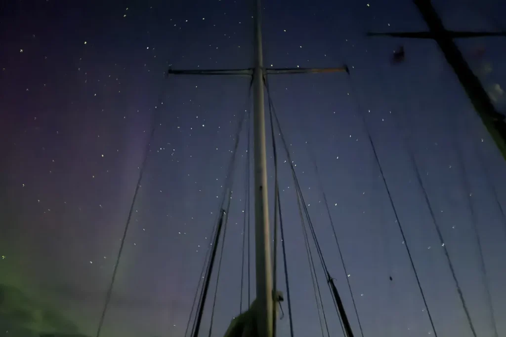 Maszt jachtu nocą na tle zorzy polarnej
